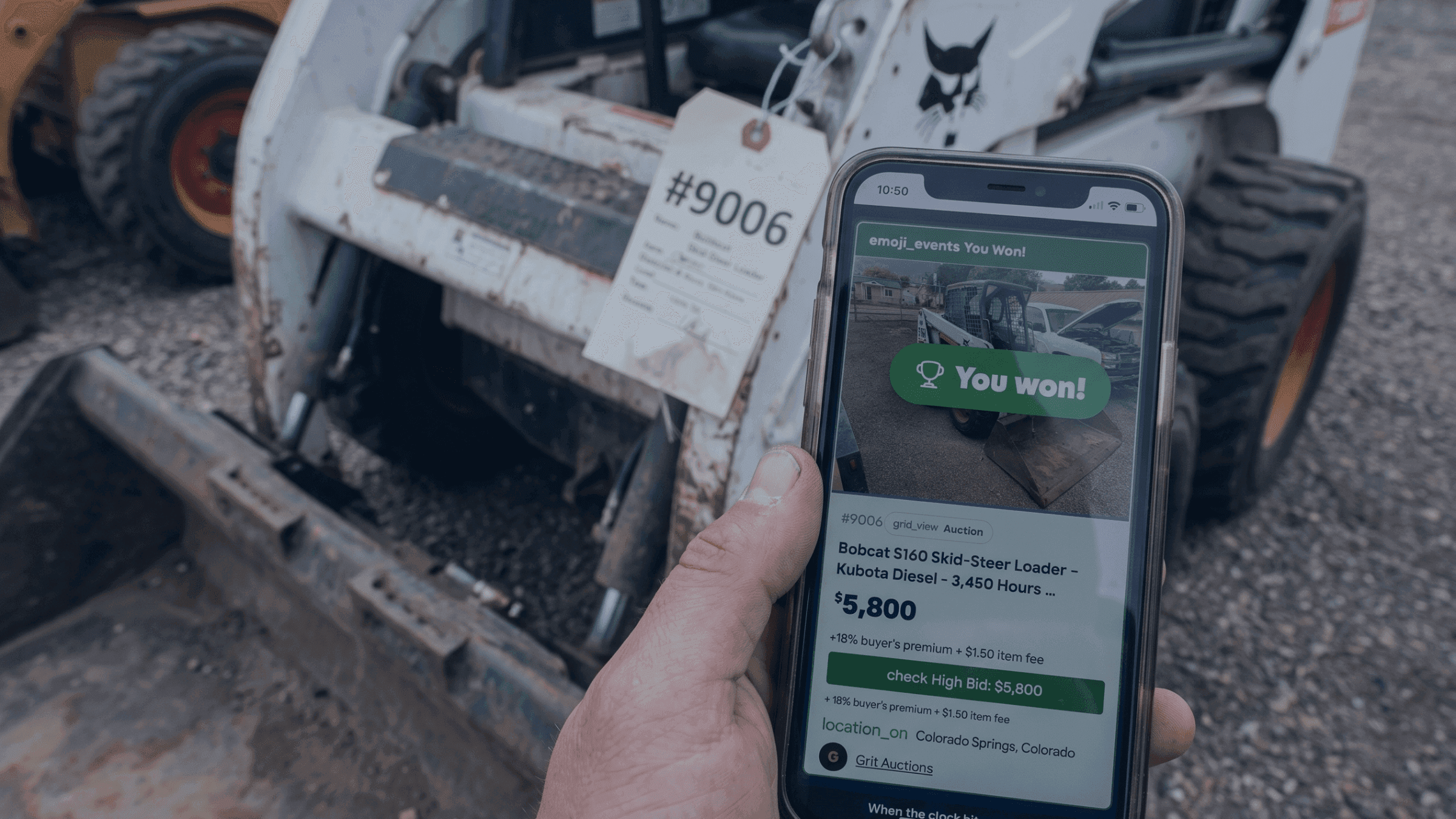 Hand holding a smartphone displaying a winning bid for a Bobcat skid-steer loader.